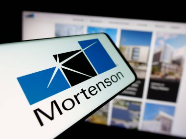 Stuttgart, Almanya - 05-17-2025: İnşaat işletmeleri M.A. logolu akıllı telefon Mortenson Şirketi web sitesinin önünde ekranda. Telefon ekranının merkez soluna odaklan.