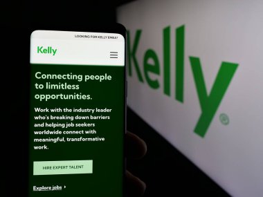 Stuttgart, Almanya - 05-17-2025: ABD 'li personel şirketi Kelly Services Inc.' in web sayfası ile akıllı telefon sahibi kişi logonun önünde ekranda. Telefon ekranının merkezine odaklan.