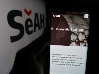 Stuttgart, Almanya - 05-17-2025: Koreli şirket SeAh Steel Holding Corp 'un internet sayfası ile logo önünde cep telefonu tutan kişi. Telefon ekranının merkezine odaklan.