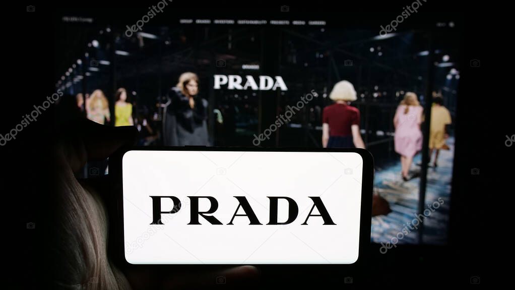 Stuttgart, Germany - 05-17-2025: Person holding cellphone with logo of luxury fashion house company Prada S.p.A. on screen in front of webpage. Focus on phone display.