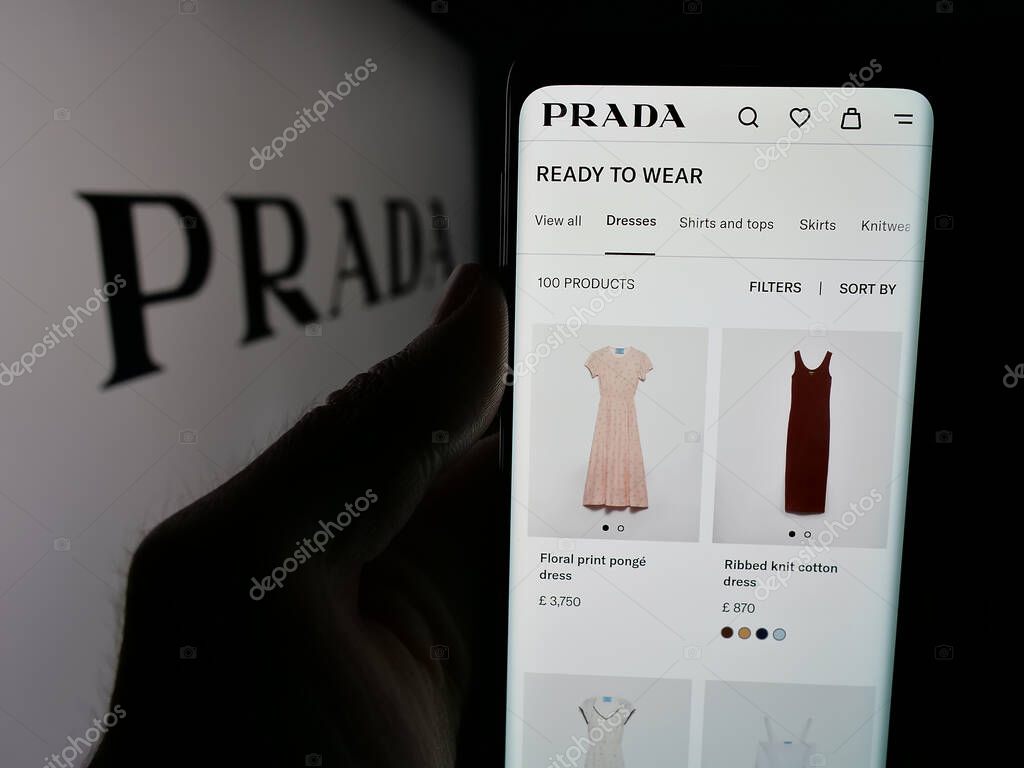 Stuttgart, Germany - 05-17-2025: Person holding cellphone with webpage of luxury fashion house company Prada S.p.A. on screen in front of logo. Focus on center of phone display.