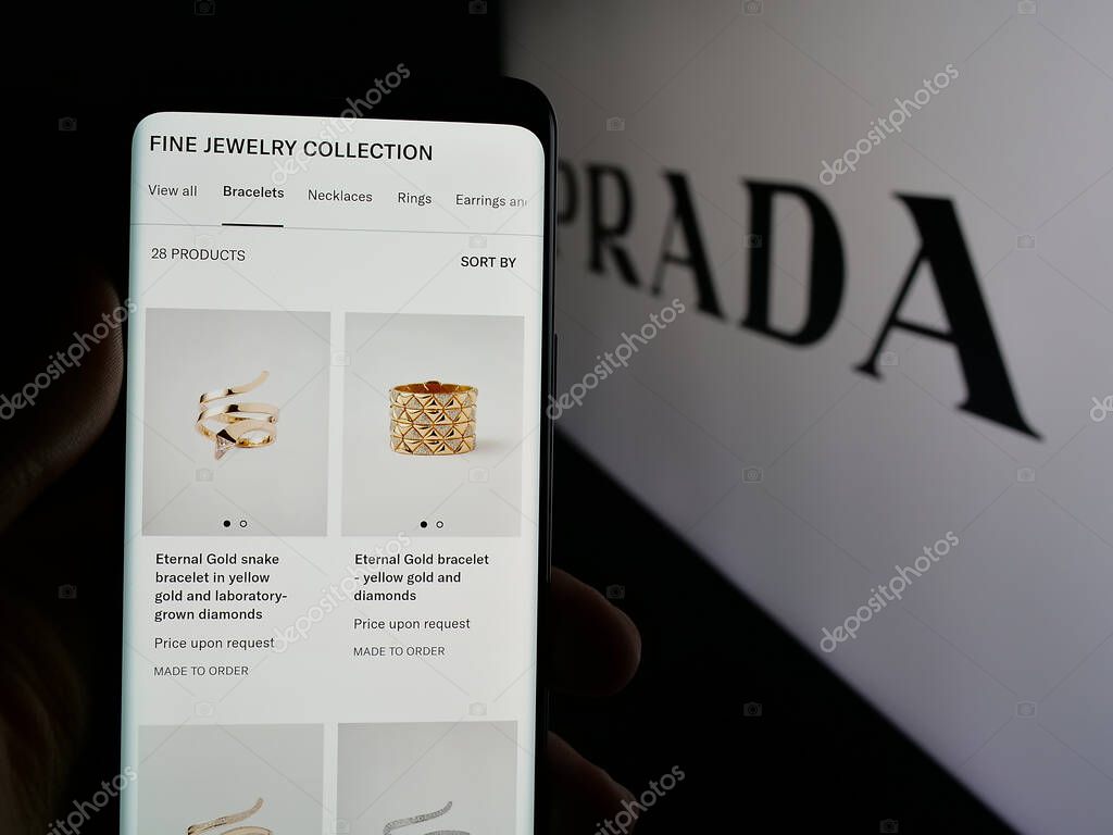 Stuttgart, Germany - 05-17-2025: Person holding smartphone with web page of luxury fashion house company Prada S.p.A. on screen in front of logo. Focus on center of phone display.