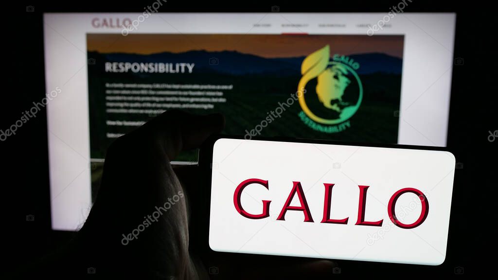 Stuttgart, Germany - 05-17-2025: Person holding mobile phone with logo of US wine producing company E. J. Gallo Winery on screen in front of web page. Focus on phone display.