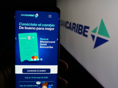 Stuttgart, Almanya - 05-18-2025: Banco del Caribe C.A. şirketinin internet sayfası ile cep telefonu tutan kişi Logonun önündeki ekranda (Bancaribe). Telefon ekranının merkezine odaklan.