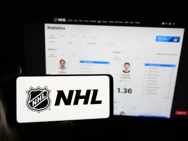 Stuttgart, Almanya - 05-18-2025: Ulusal Hokey Ligi (NHL) logosuna sahip akıllı telefonu web sitesinin önünde tutan kişi. Telefon ekranına odaklan.