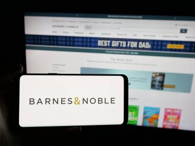 Stuttgart, Almanya - 05-25-2025: ABD 'li kitap satış şirketi Barnes ve Noble Inc.' in logosunu elinde bulunduran kişi web sitesinin önünde ekranda. Telefon ekranına odaklan.