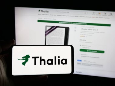 Stuttgart, Almanya - 05-25-2025: Alman kitapçı firması Thalia Bucher GmbH 'in logosunun bulunduğu akıllı telefonu web sitesinin önünde tutan kişi. Telefon ekranına odaklan.