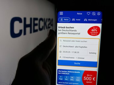 Stuttgart, Almanya - 05-25-2025: Alman fiyat karşılaştırma şirketi Check24 GmbH 'nin internet sayfası olan cep telefonu sahibi kişi logonun önünde ekranda. Telefon ekranının merkezine odaklan.