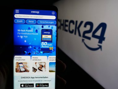 Stuttgart, Almanya - 05-25-2025: Alman fiyat karşılaştırma şirketi Check24 GmbH 'nin web sayfası ile akıllı telefon sahibi kişi logonun önünde ekranda. Telefon ekranının merkezine odaklan.