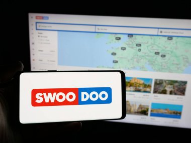 Stuttgart, Almanya - 05-25-2025: İnternet sitesinin önünde SWOODOO arama platformunun logosuna sahip akıllı telefon sahibi kişi. Telefon ekranına odaklan.