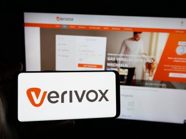 Stuttgart, Almanya - 05-25-2025: Alman fiyat karşılaştırma şirketi Verivox GmbH logosuna sahip akıllı telefon sahibi kişi web sitesinin önünde ekranda. Telefon ekranına odaklan.