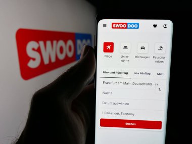 Stuttgart, Almanya - 05-25-2025: Uçuş arama platformu SWOODOO 'nun web sayfası olan akıllı telefonu logonun önünde tutan kişi. Telefon ekranının merkezine odaklan.