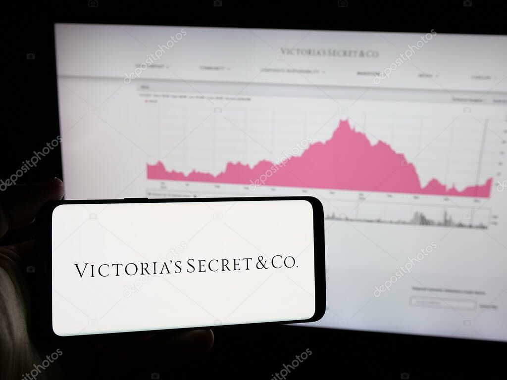 Stuttgart, Germany - 05-18-2025: Person holding smartphone with logo of US lingerie company Victoria's Secret Co. on screen in front of website. Focus on phone display.