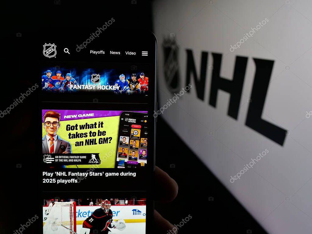 Stuttgart, Germany - 05-18-2025: Person holding cellphone with webpage of National Hockey League (NHL) on screen in front of logo. Focus on center of phone display.
