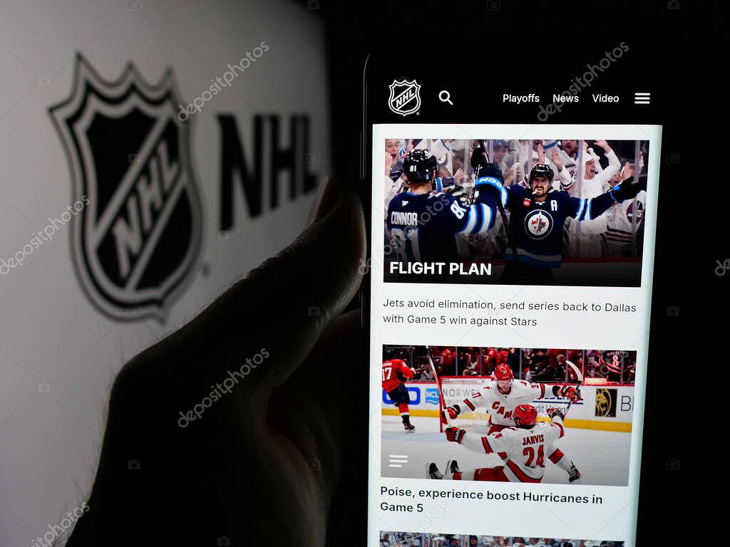 Stuttgart, Germany - 05-18-2025: Person holding smartphone with web page of National Hockey League (NHL) on screen in front of logo. Focus on center of phone display.