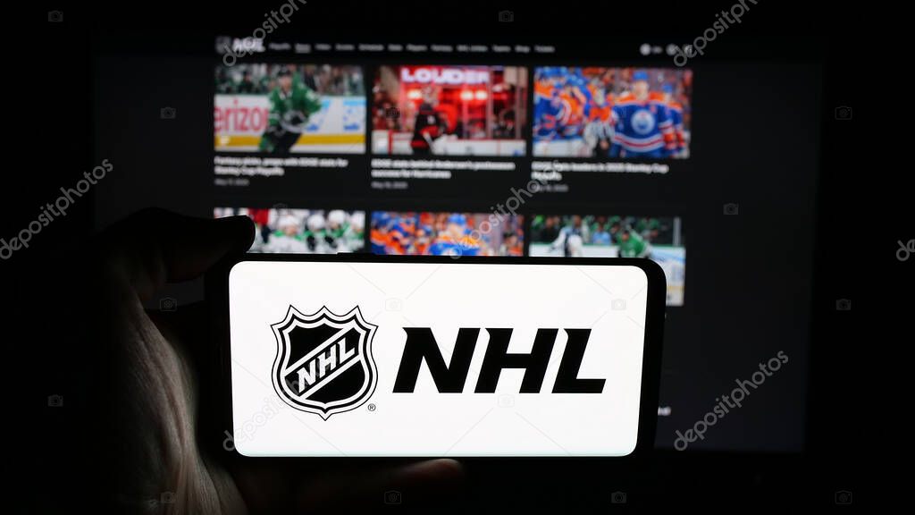 Stuttgart, Germany - 05-18-2025: Person holding cellphone with logo of National Hockey League (NHL) on screen in front of webpage. Focus on phone display.