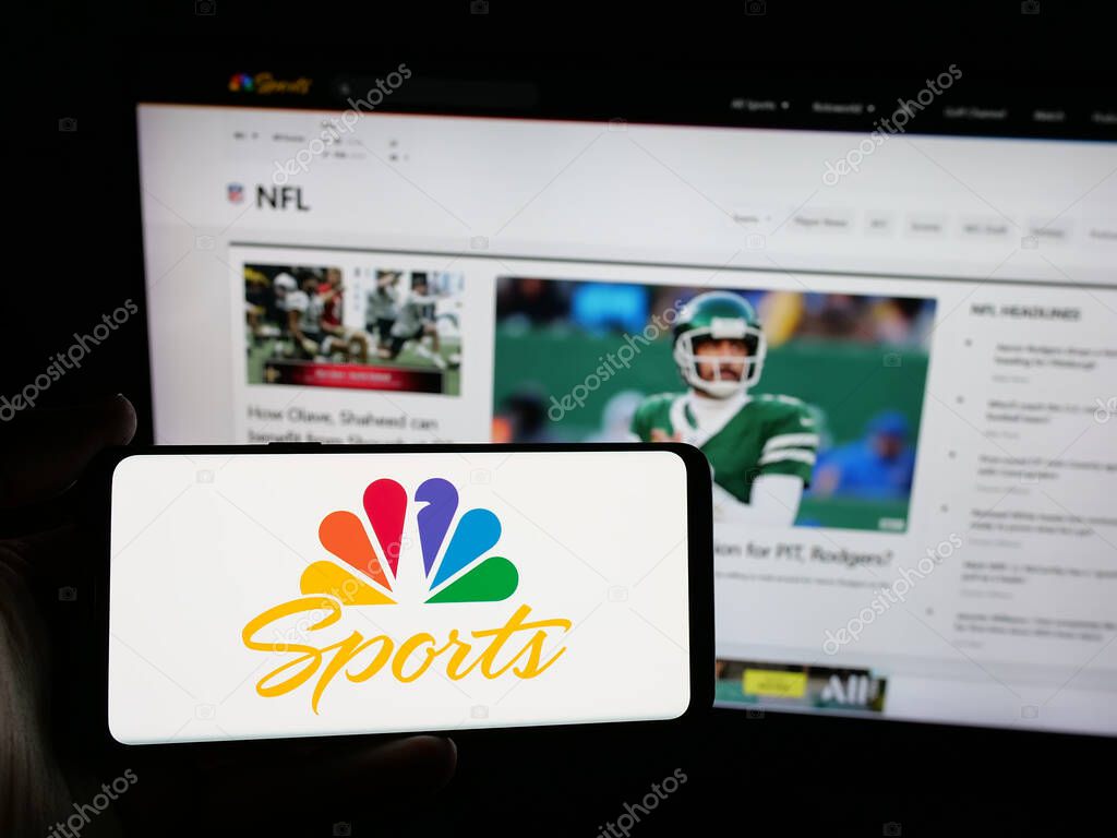 Stuttgart, Germany - 05-25-2025: Person holding smartphone with logo of US television channel NBC Sports (NBCSports) on screen in front of website. Focus on phone display.
