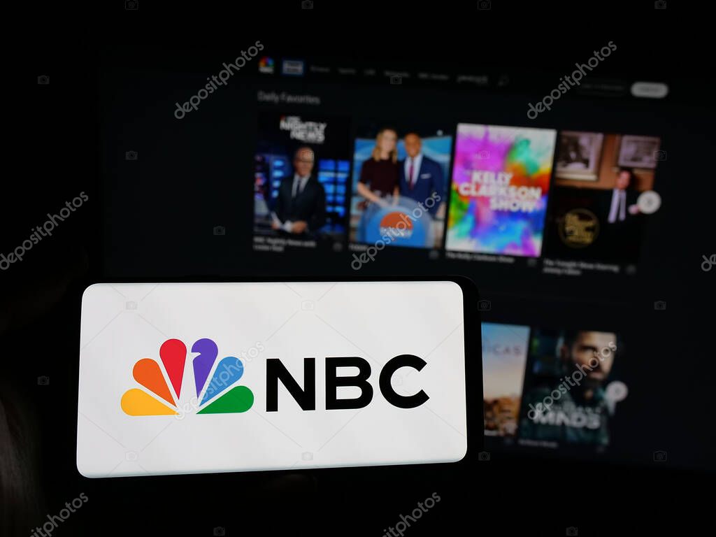 Stuttgart, Germany - 05-25-2025: Person holding smartphone with logo of network National Broadcasting Company (NBC) on screen in front of website. Focus on phone display.
