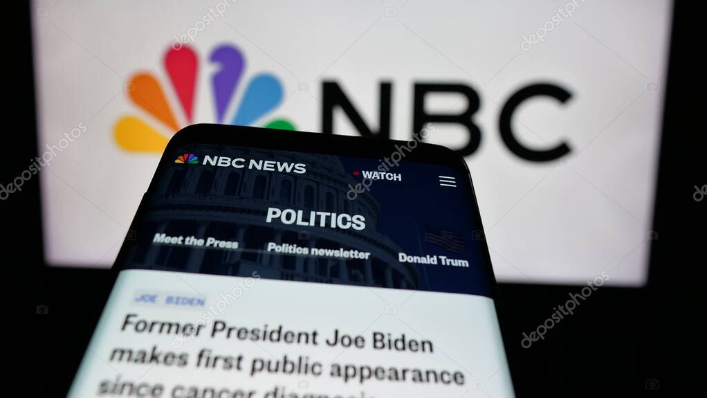 Stuttgart, Germany - 05-25-2025: Mobile phone with website of network National Broadcasting Company (NBC) on screen in front of logo. Focus on top-left of phone display.