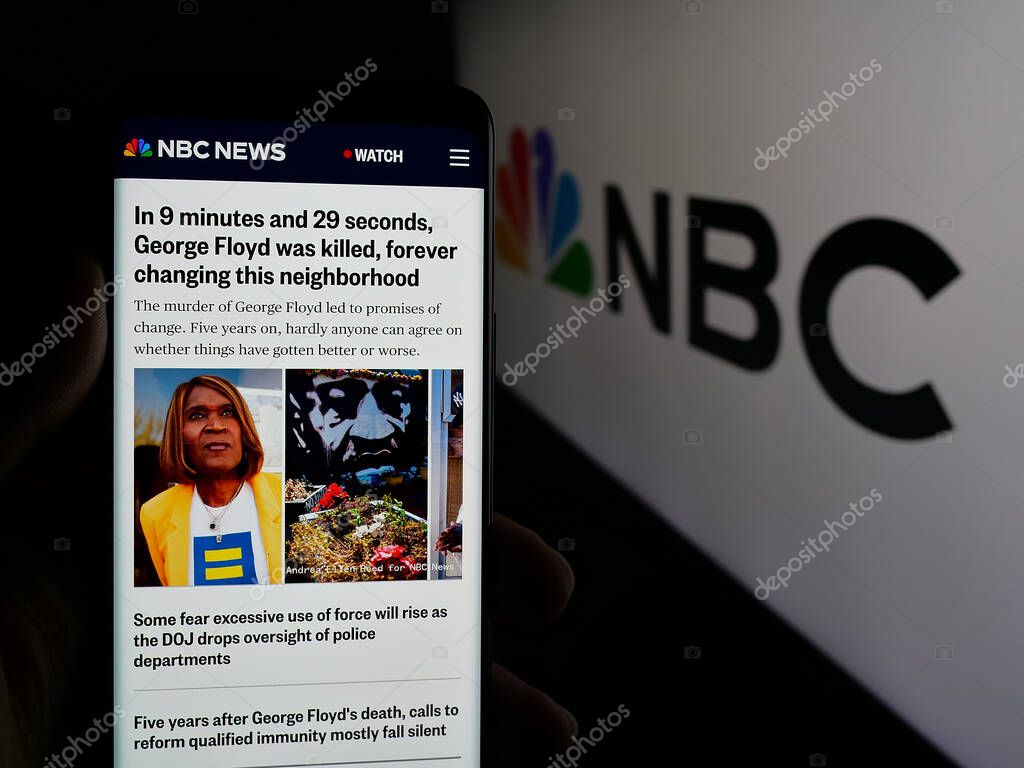 Stuttgart, Germany - 05-25-2025: Person holding smartphone with web page of network National Broadcasting Company (NBC) on screen in front of logo. Focus on center of phone display.