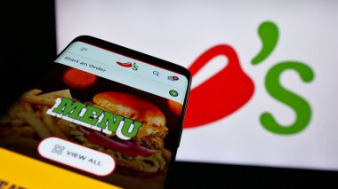 Stuttgart, Almanya - 05-25-2025: ABD 'li restoran zinciri şirketi Chili' s Grill Bar 'ın web sitesiyle birlikte logo önünde cep telefonu. Telefon ekranının sol üst kısmına odaklan.