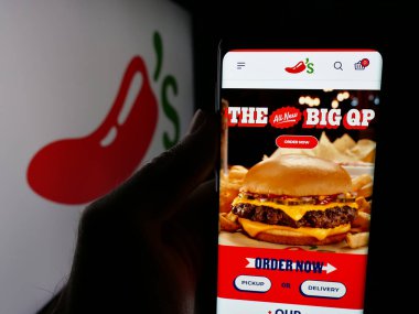 Stuttgart, Almanya - 05-25-2025: ABD 'li restoran zinciri şirketi Chili' s Grill Bar 'ın web sayfası ile akıllı telefon sahibi kişi logonun önünde ekranda. Telefon ekranının merkezine odaklan.