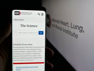 Stuttgart, Almanya - 05-25-2025: ABD sağlık enstitüsü NHLBI 'ın internet sayfası olan cep telefonu logosu önünde ekranda. Telefon ekranının merkezine odaklan.