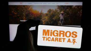 Stuttgart, Almanya - 05-25-2025: Türk perakende şirketi Migros Ticaret A.S. 'in logosunun bulunduğu cep telefonu web sayfası önünde ekranda. Telefon ekranına odaklan.