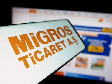 Stuttgart, Almanya - 05-25-2025: Türk perakende şirketi Migros Ticaret A.S. 'in logosuna sahip akıllı telefon web sitesinin önünde ekranda. Telefon ekranının soluna odaklan.