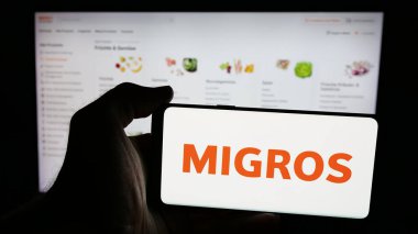 Stuttgart, Almanya - 05-25-2025: İsviçreli süpermarket şirketi Migros 'un logosunun bulunduğu cep telefonu web sayfası önünde ekranda. Telefon ekranına odaklan.