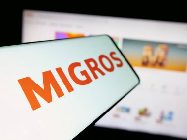 Stuttgart, Almanya - 05-25-2025: İsviçreli süpermarket şirketi Migros 'un logosunu içeren akıllı telefon web sitesinin önünde ekranda. Telefon ekranının merkez soluna odaklan.