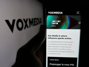 Stuttgart, Almanya - 05-26-2025: ABD 'li Vox Media Inc. (VoxMedia) şirketinin web sayfası logonun önünde duran kişi. Telefon ekranının merkezine odaklan.
