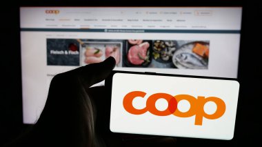 Stuttgart, Almanya - 05-26-2025: İsviçreli perakende şirketi Coop Genossenschaft 'ın logosunun bulunduğu cep telefonu web sayfası önünde ekranda. Telefon ekranına odaklan.