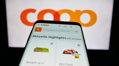 Stuttgart, Almanya - 05-26-2025: İsviçre 'li perakende şirketi Coop Genossenschaft' ın web sitesi ile birlikte logo önünde cep telefonu. Telefon ekranının sol üst kısmına odaklan.