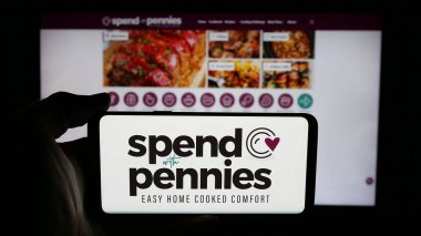 Stuttgart, Almanya - 05-26-2025: Web sayfası önünde ekranda, üzerinde Harcamalarla Harca (SWP Media Ltd.) şirketinin logosu olan cep telefonu bulunan kişi. Telefon ekranına odaklan.