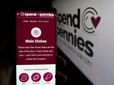 Stuttgart, Almanya - 05-26-2025: Logonun önündeki ekranda, şirket Spend With Pennies (SWP Media Ltd.) web sayfası ile cep telefonu bulunduran kişi. Telefon ekranının merkezine odaklan.