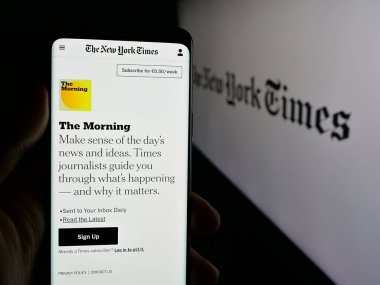 Stuttgart, Almanya - 05-27-2025: Amerikan günlük gazetesi The New York Times 'ın (NYT) internet sayfası logo önünde cep telefonu tutan kişi. Telefon ekranının merkezine odaklan.