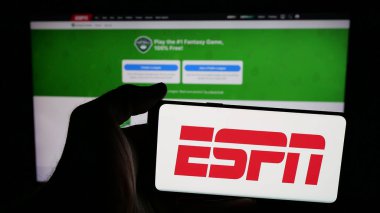 Stuttgart, Almanya - 05-27-2025: İnternet sayfası önünde ekranda ABD kablolu televizyon kanalı ESPN logosu bulunan cep telefonu sahibi kişi. Telefon ekranına odaklan.