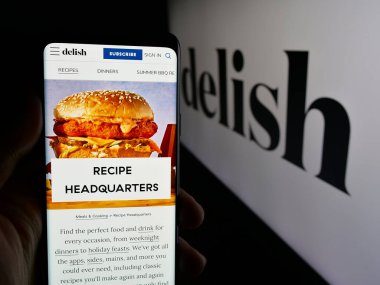Stuttgart, Almanya - 05-27-2025: ABD gıda çevrimiçi dergisi Delish.com 'un (Hearst) internet sayfası ile akıllı telefon taşıyan kişi logonun önünde ekranda. Telefon ekranının merkezine odaklan.