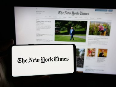 Stuttgart, Almanya - 05-27-2025: İnternet sitesi önünde üzerinde ABD 'li günlük gazete The New York Times (NYT) logosu bulunan kişi. Telefon ekranına odaklan.