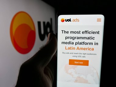 Stuttgart, Almanya - 05-27-2025: Brezilya web platformu Universo Online 'ın (UOL) web sayfası olan akıllı telefonu logonun önünde tutan kişi. Telefon ekranının merkezine odaklan.
