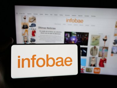 Stuttgart, Almanya - 05-27-2025: Arjantin online gazetesi Infobae 'nin logosunu elinde tutan kişi web sitesinin önünde ekranda. Telefon ekranına odaklan.