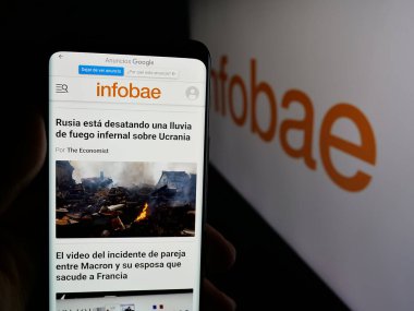Stuttgart, Almanya - 05-27-2025: Arjantin online gazetesi Infobae 'nin internet sayfasını elinde tutan kişi logonun önünde ekranda. Telefon ekranının merkezine odaklan.