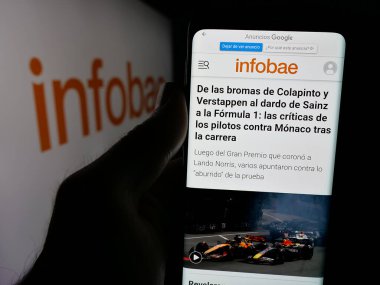 Stuttgart, Almanya - 05-27-2025: Arjantin online gazetesi Infobae 'nin internet sayfası ile logo önünde cep telefonu tutan kişi. Telefon ekranının merkezine odaklan.