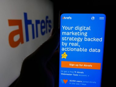 Stuttgart, Almanya - 05-29-2025: SEO araç şirketi Ahrefs Pte 'nin web sayfası ile akıllı telefon tutan kişi. Ltd. Logonun önünde ekranda. Telefon ekranının merkezine odaklan.