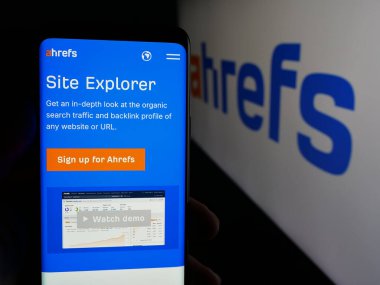 Stuttgart, Almanya - 05-29-2025: SEO araç şirketi Ahrefs Pte 'nin internet sayfası ile cep telefonu tutan kişi. Ltd. Logonun önünde ekranda. Telefon ekranının merkezine odaklan.