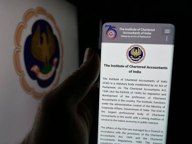 Stuttgart, Almanya - 05-29-2025: Tüzük Muhasebeciler Enstitüsü (ICAI) internet sayfası logonun önünde cep telefonu tutan kişi. Telefon ekranının merkezine odaklan.