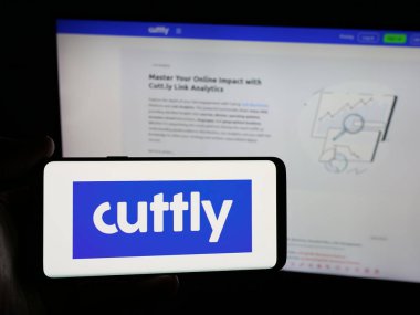 Stuttgart, Almanya - 05-29-2025: İnternet sitesinin önünde Cutt.ly (Bağlantı Yönetim Platformu Logosu) logosu olan akıllı telefon sahibi kişi. Telefon ekranına odaklan.