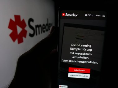 Stuttgart, Almanya - 05-29-2025: İsviçreli e-öğrenim şirketi Smedex AG 'nin web sayfası ile akıllı telefon sahibi kişi logonun önünde ekranda. Telefon ekranının merkezine odaklan.