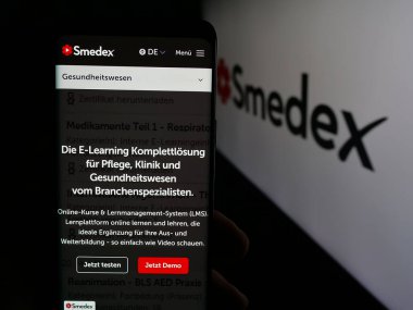 Stuttgart, Almanya - 05-29-2025: İsviçreli e-öğrenim şirketi Smedex AG 'nin web sayfası ile logo önünde cep telefonu tutan kişi. Telefon ekranının merkezine odaklan.